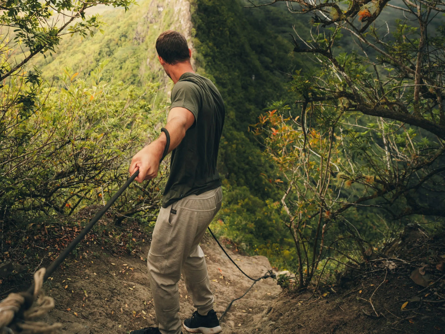 A man hiking with a rope in the forest