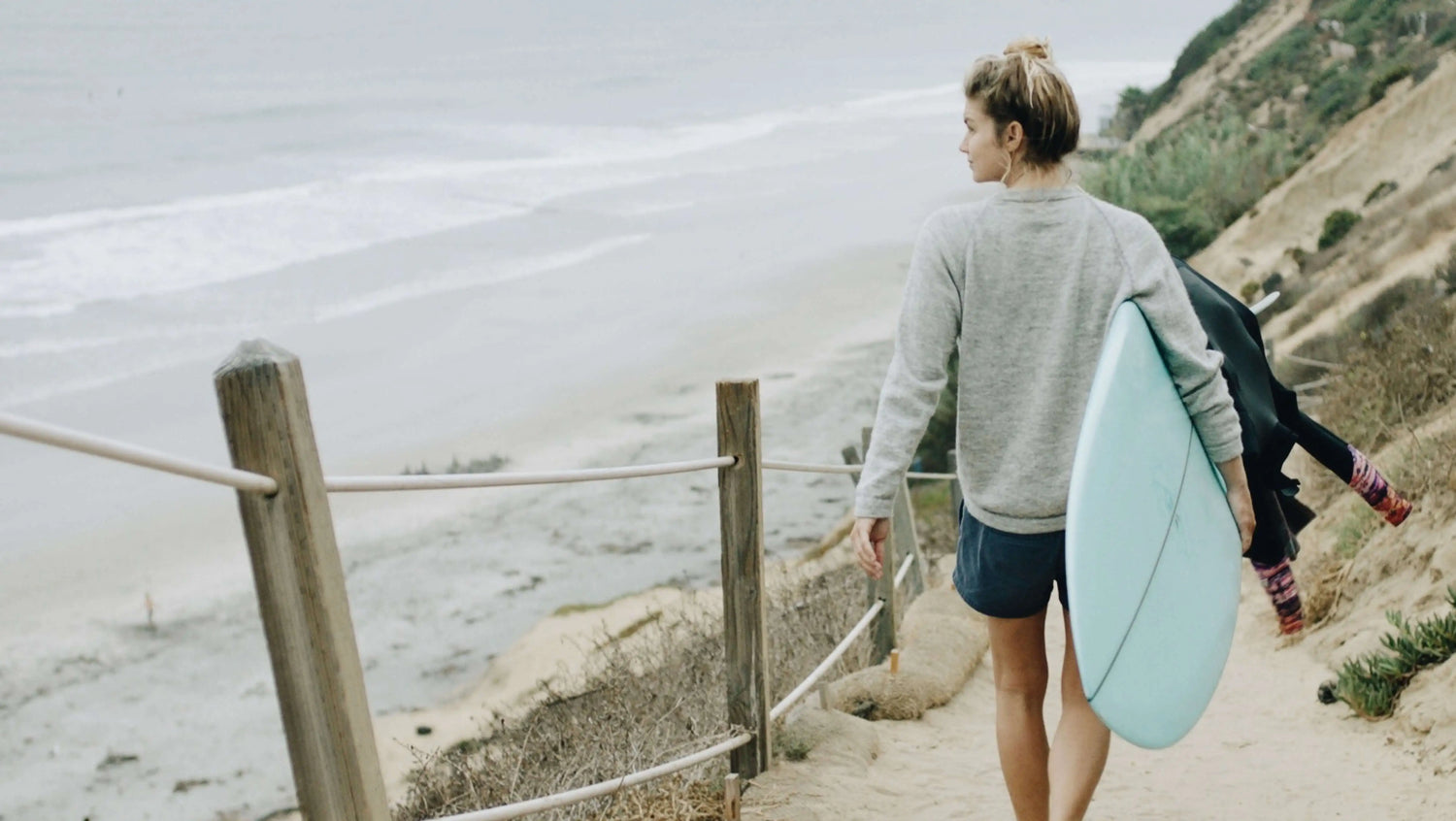 Surfer wearing Paka crewneck with surfboard