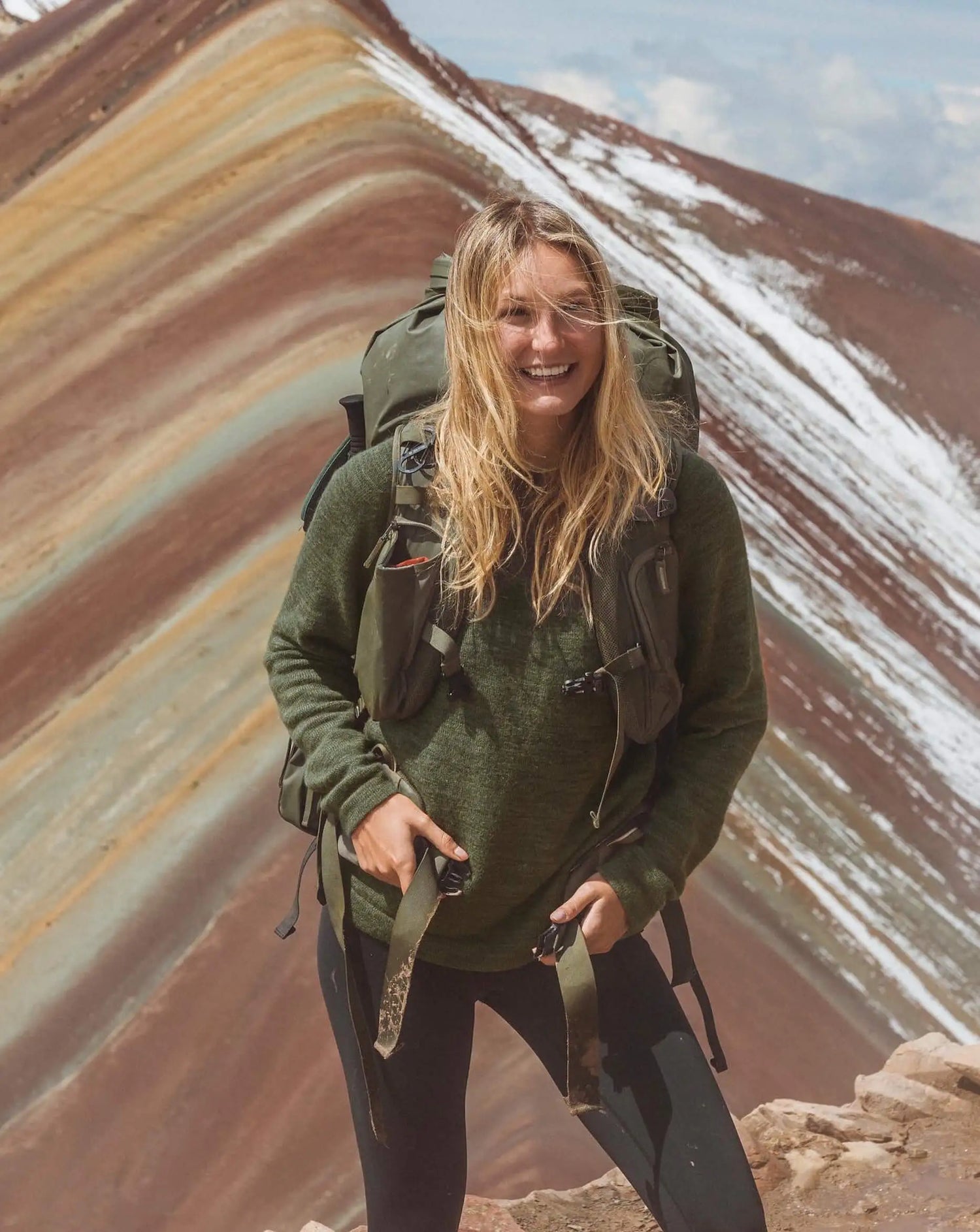 Girl wearing sweater with backpack in front of mountains