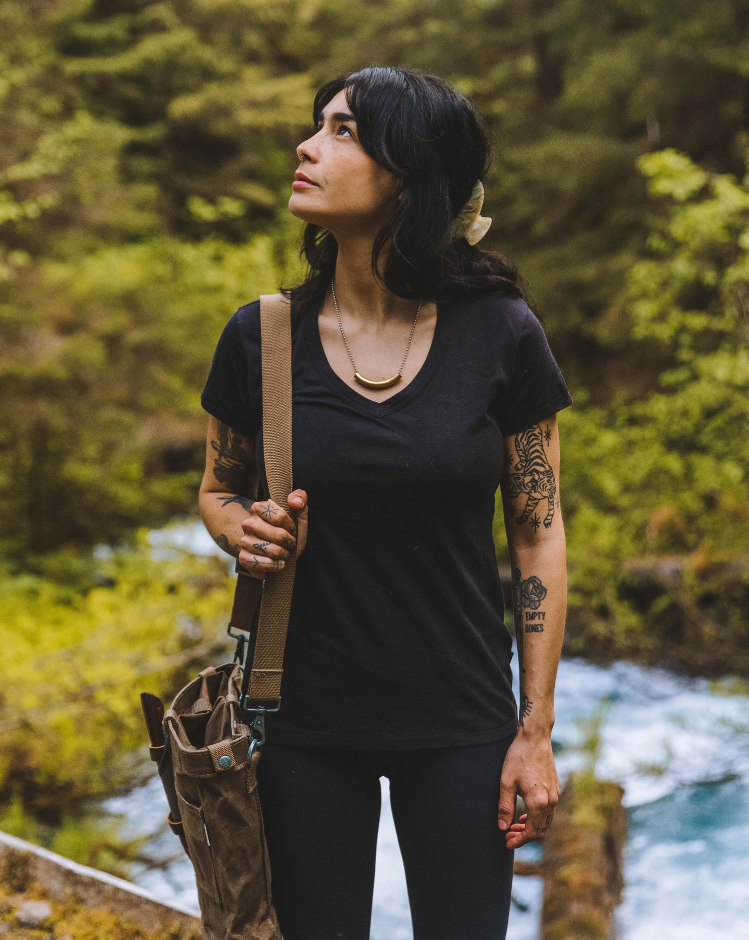 Woman looking to the right in her black alpaca v-neck tee by a river