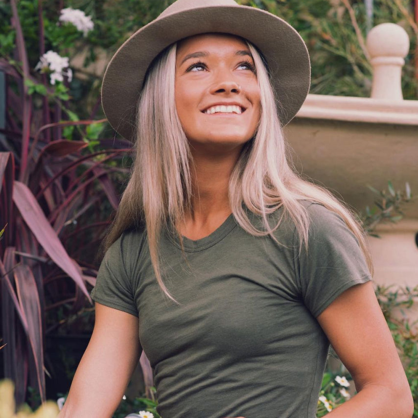 A smiling girl wearing a hat and a green alpaca tee