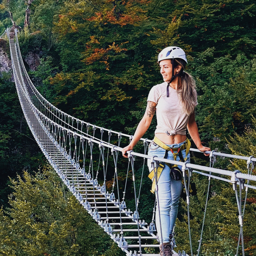 a woman crossing a suspension bridge in her alpaca tee