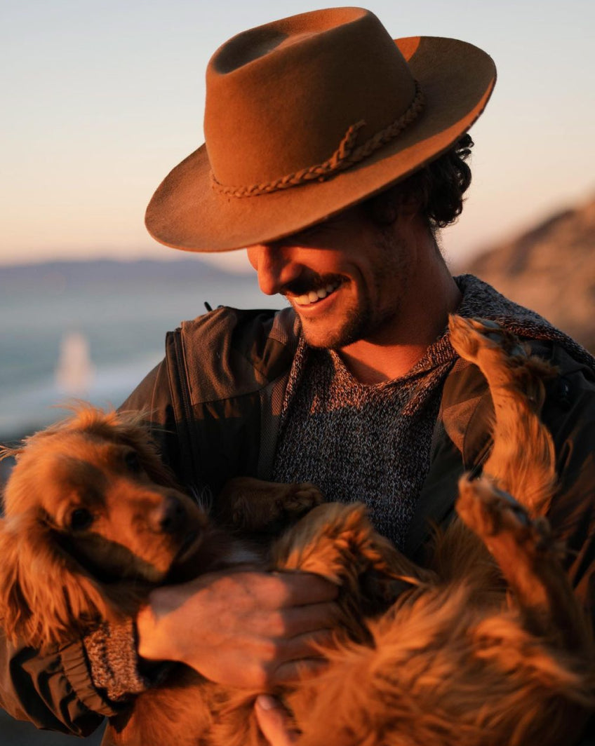 A man holding his dog during the sunset