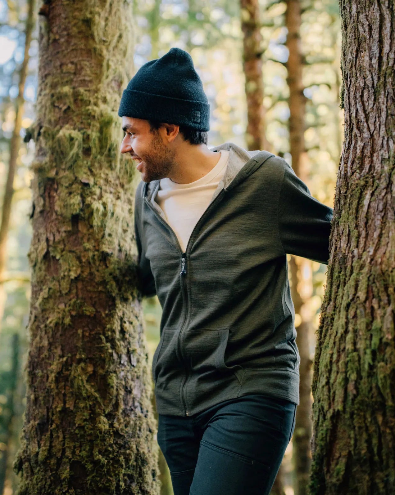 A man wearing a green Breathe Full Zip among the trees