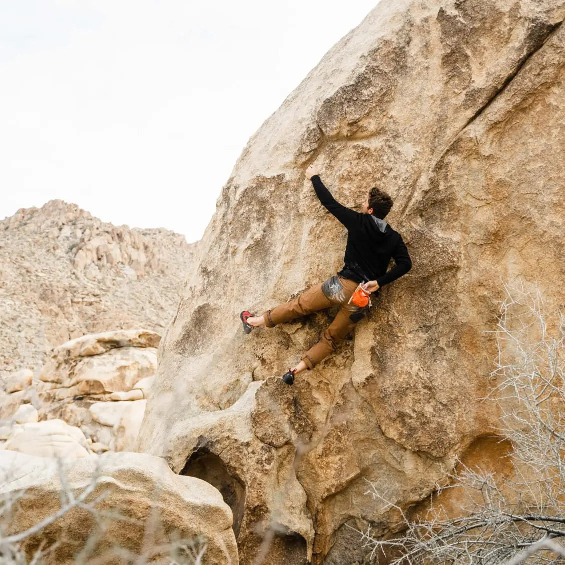 A man wearing a black Men's Full Zip climbing rocks 