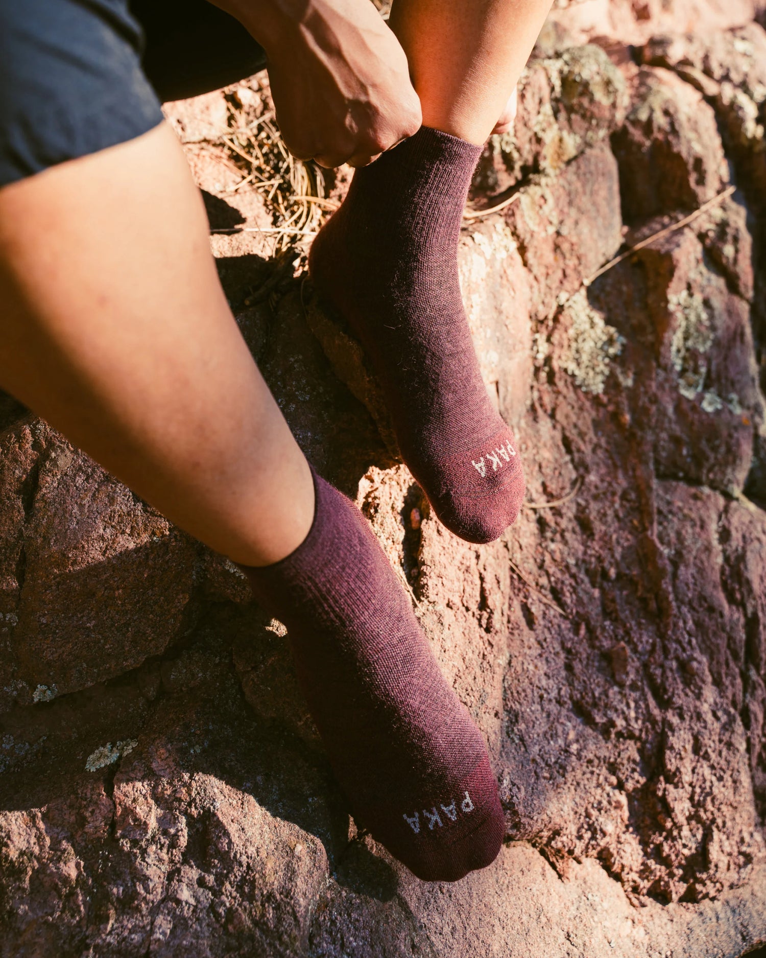 Close-up of Trail 1/4 crew socks in charcoal on model’s feet on a rocky trail showing mid-ankle height and textured knit