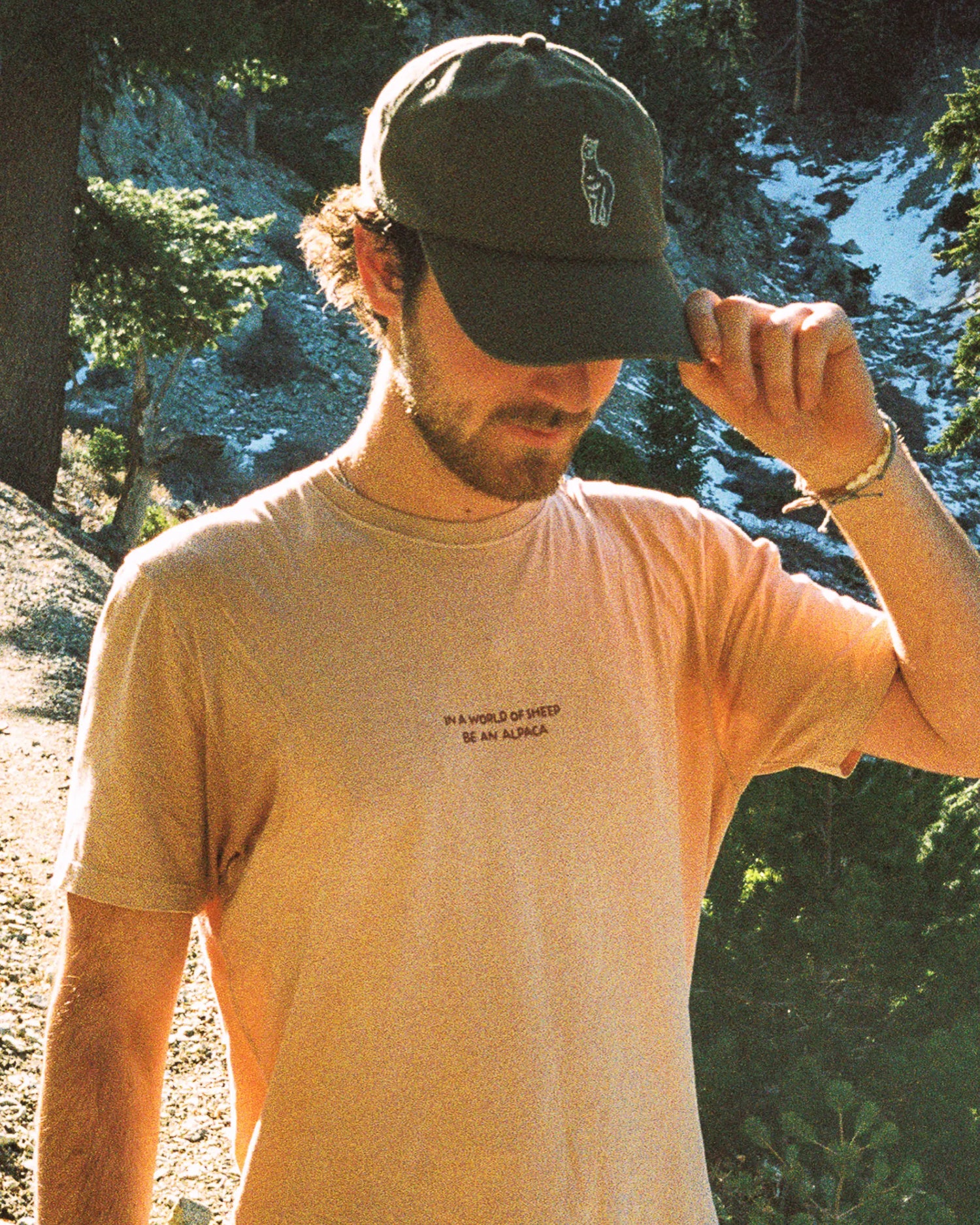 Man Outdoors Touching Brim of Sebastian Alpaca Graphic Hat in Charcoal Grey – PAKA Apparel
