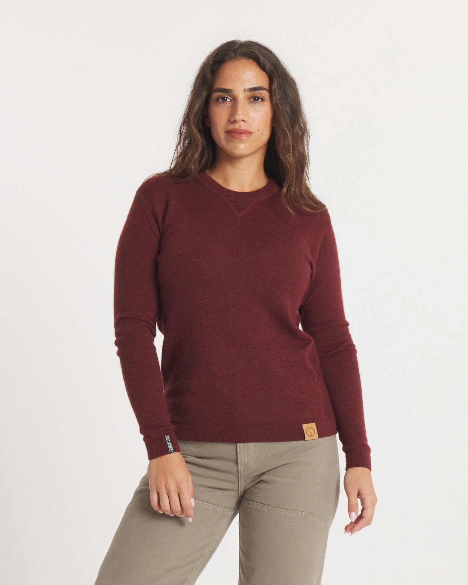Front view of The Lightweight Crew alpaca crewneck in burgundy showing V stitch neckline and leather logo patch on white