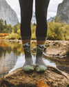 Someone wearing our Alpaca mountain socks over a rock in a river