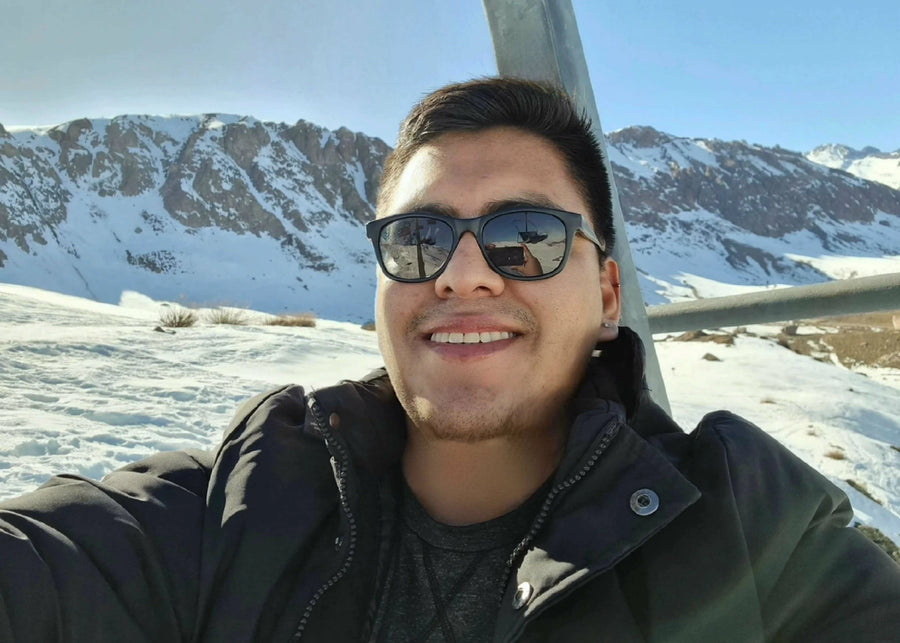Victor wearing sunglasses and smiling with snowy mountains in the background 