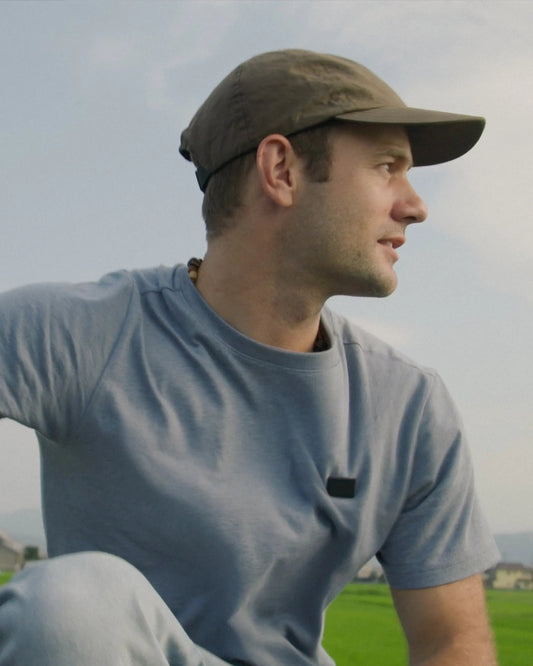 Man standing outdoors in a blue shirt with a mountain landscape behind him