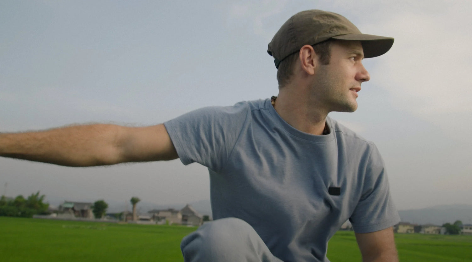 Man in a blue shirt and cap sitting in a green field