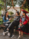 Gisella, our head of Perú smiling with two of our Paka scholars in a park in Cusco