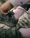 Close-up of Trail 3/4 crew sock in quail pink on foot showing ribbed knit and ankle fit with hiking shoe on rocky trail