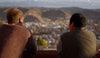 Two people look out over a mountainous landscape