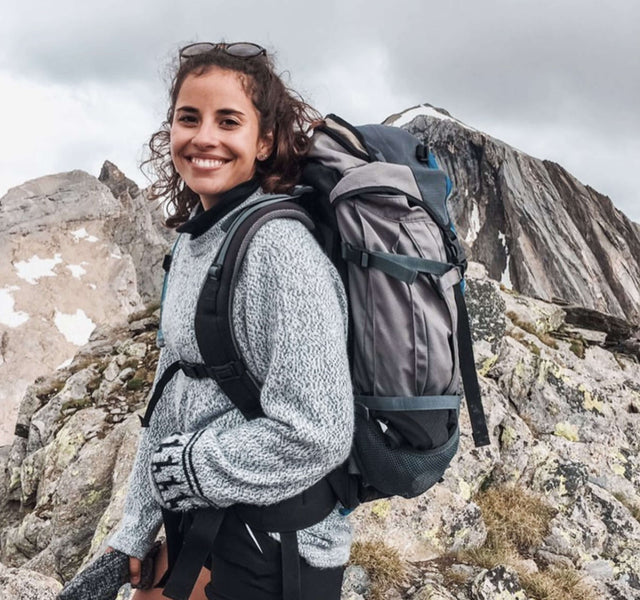 A smiling woman wearing The Costa, backpacking in the mountains 