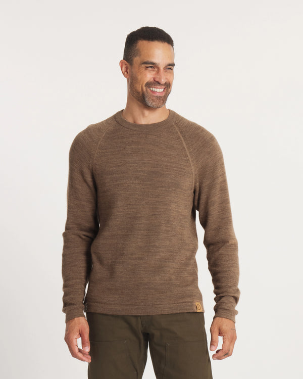 Man wearing a brown sweater and pants on a white background