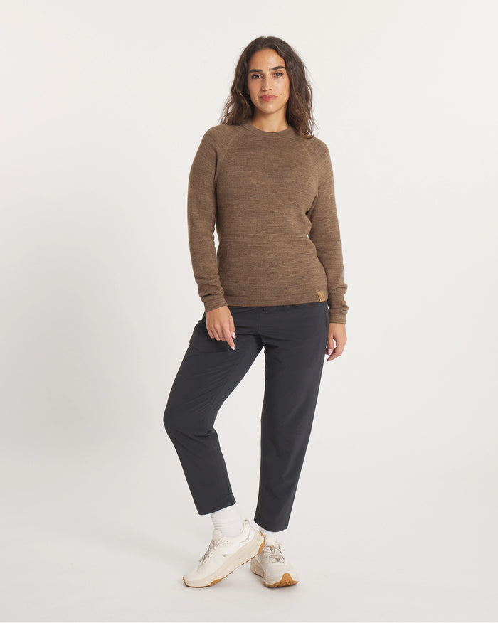 Woman wearing a brown sweater and black pants on a white background