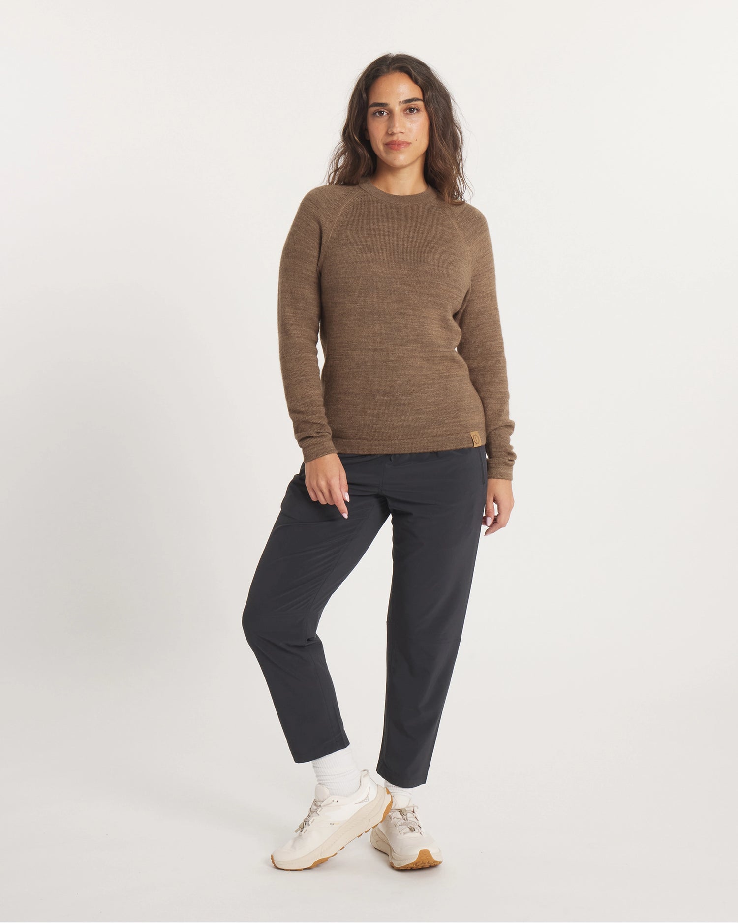 Woman wearing a brown sweater and black pants on a white background