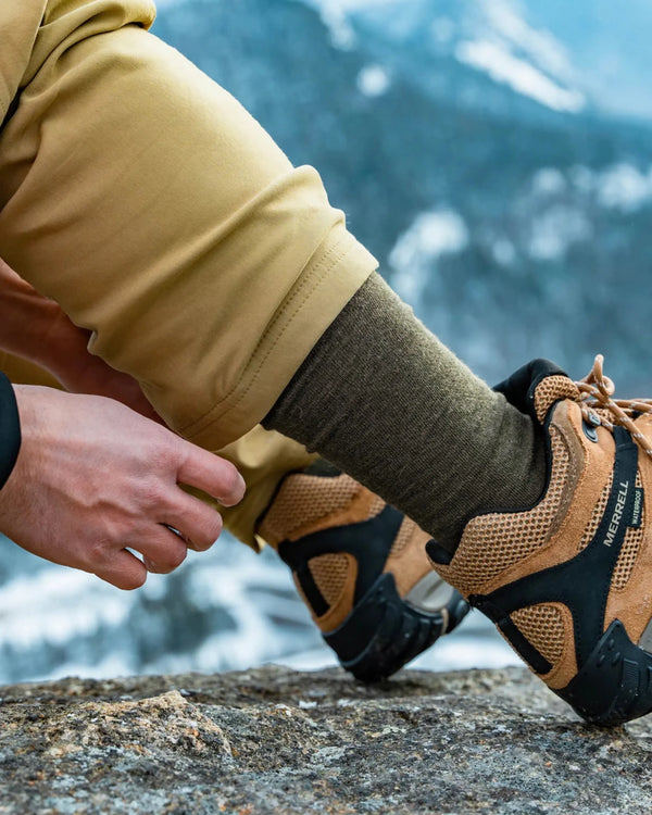 Person wearing hiking boots and pants with a mountainous background