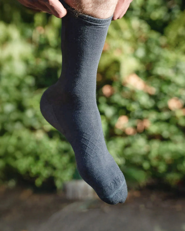 Indigo sock held up against a blurred green outdoor background