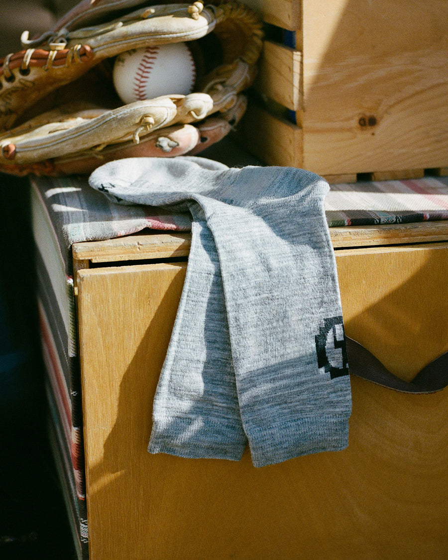 Baseball glove, ball, and sock on a wooden surface with books underneath