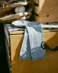 Baseball glove, ball, and sock on a wooden surface with books underneath