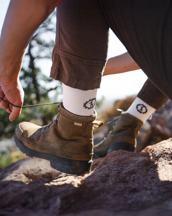 Person tying hiking boots with a blurred natural background