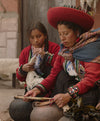 Quechua weaver showing two girls the ancient alpaca dyeing process