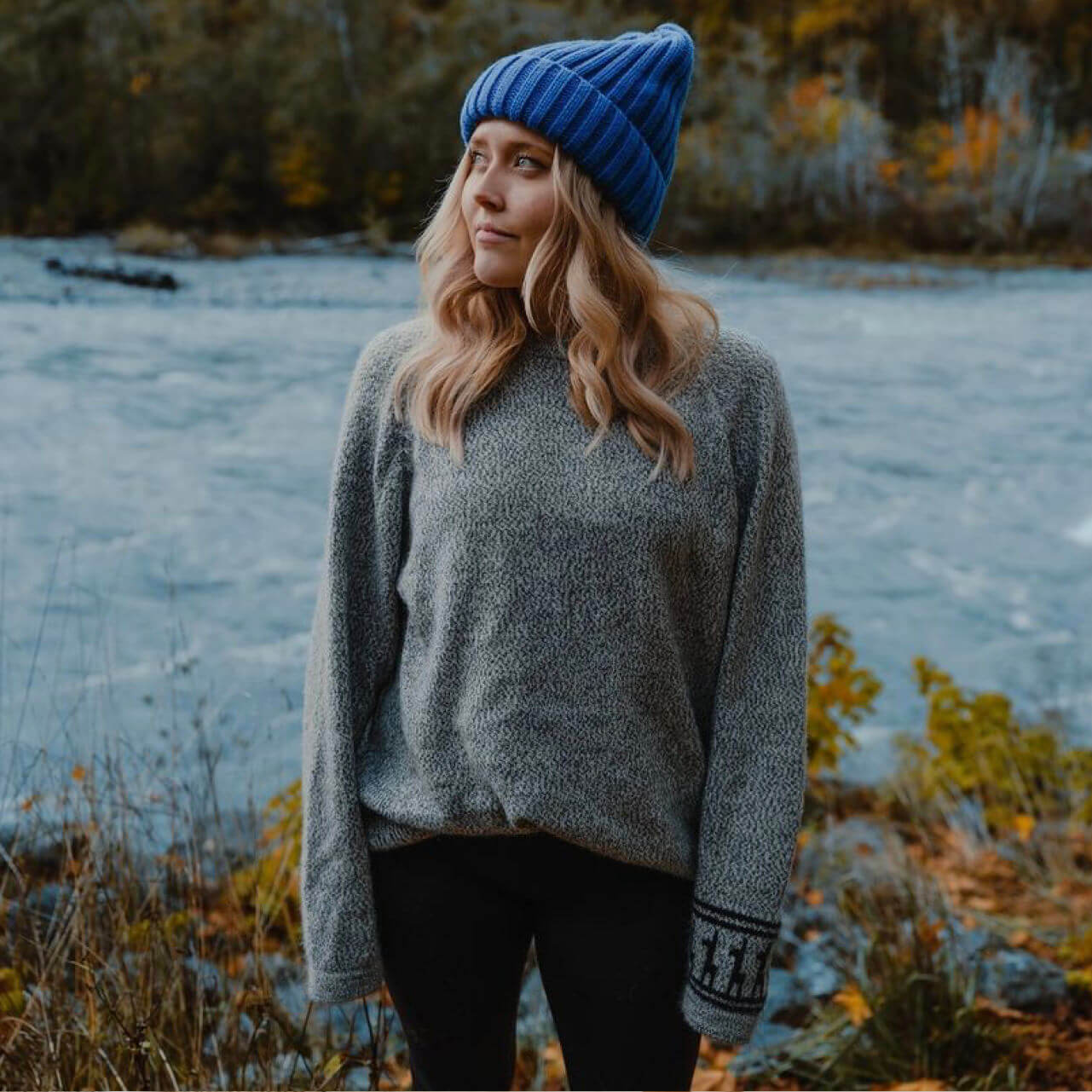 Woman wearing alpaca sweater in front of river 
