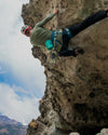 Man rock climbing wearing green alpaca base layer 