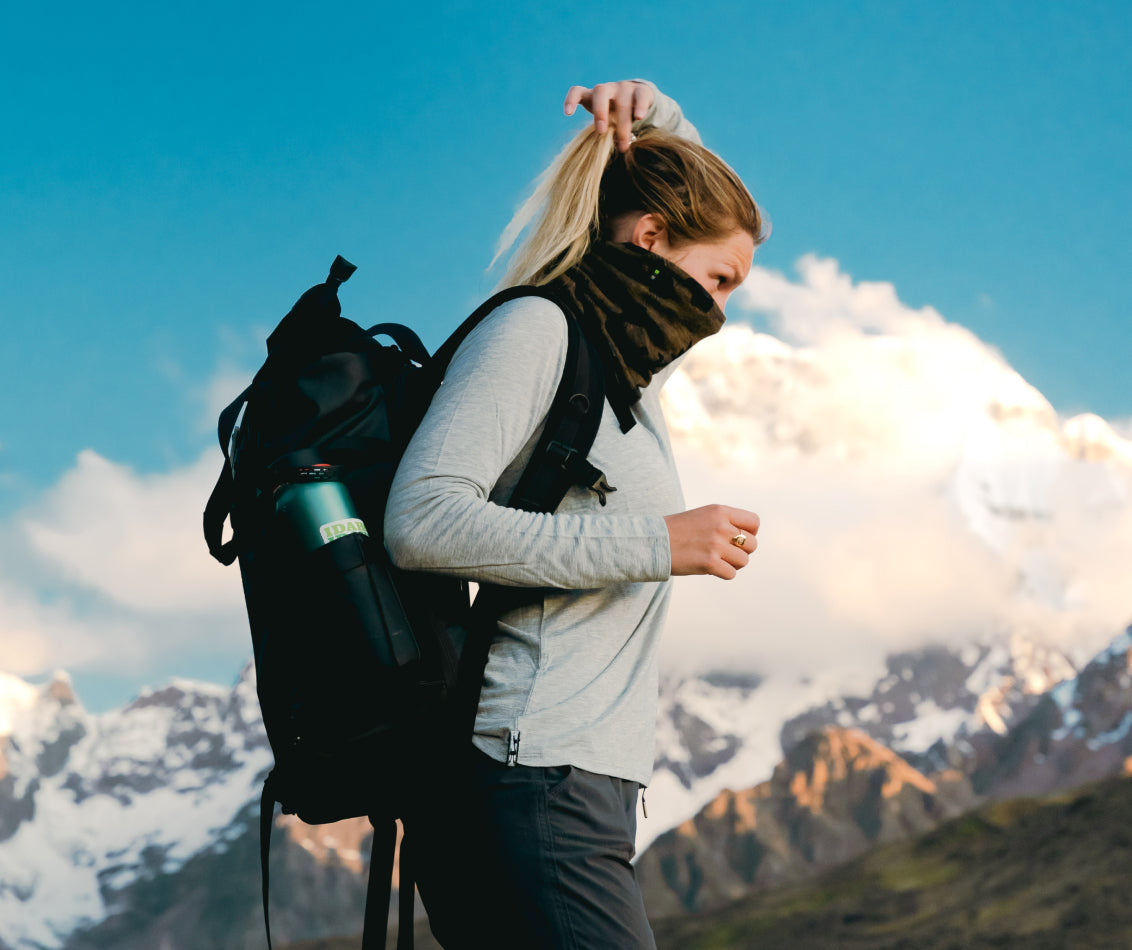 Woman with backpack standing in front of mountains in alpaca wool base layer 