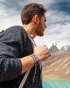 A man wearing an alpaca sweater and alpaca bracelets in front of Ausangate Mountain