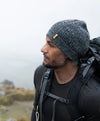 A backpacker wearing a charcoal alpaca beanie in a cloudy place