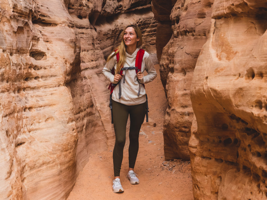 A woman wearing an ivory Breathe Women's hoodie in a canyon