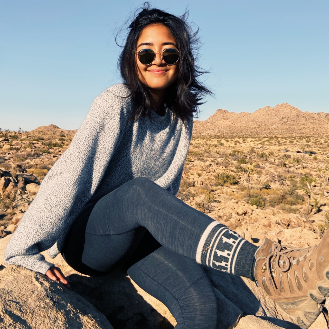 A smiling woman in a desert wearing his amazing Costa socks