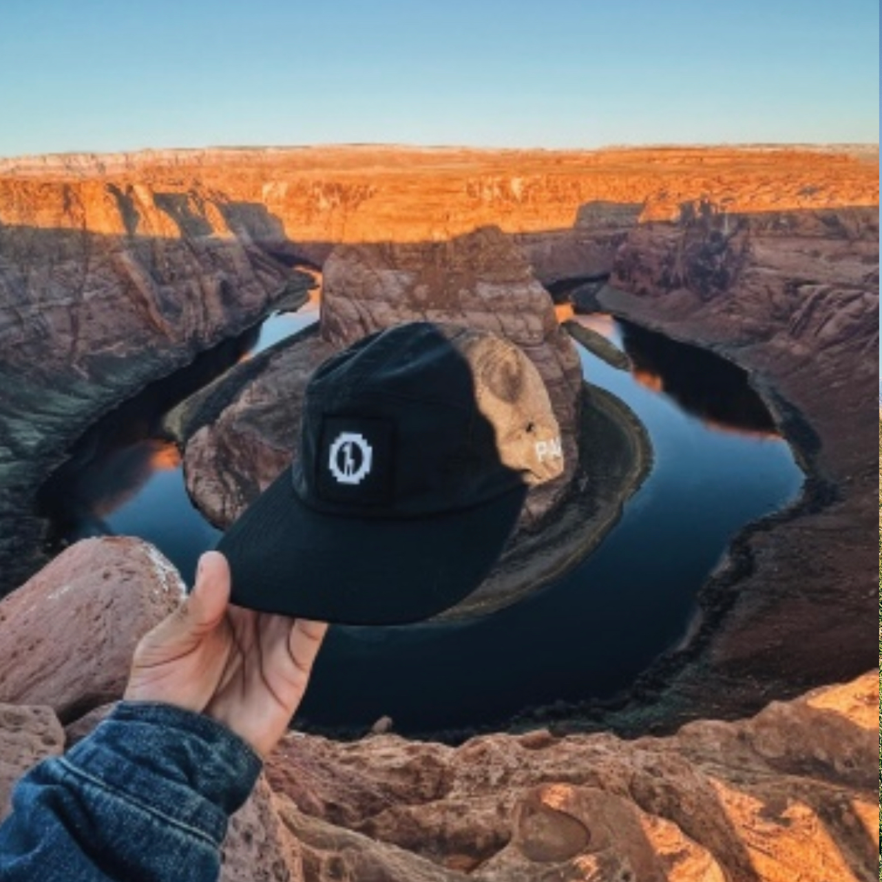 A Paka team-5 panel hat  in front of a canyon and a lake 