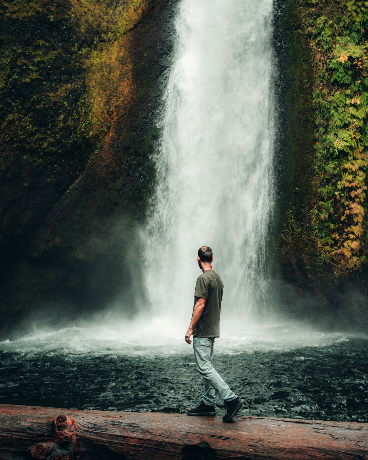 A man on his green alpaca tee looking at a beautiful waterfall