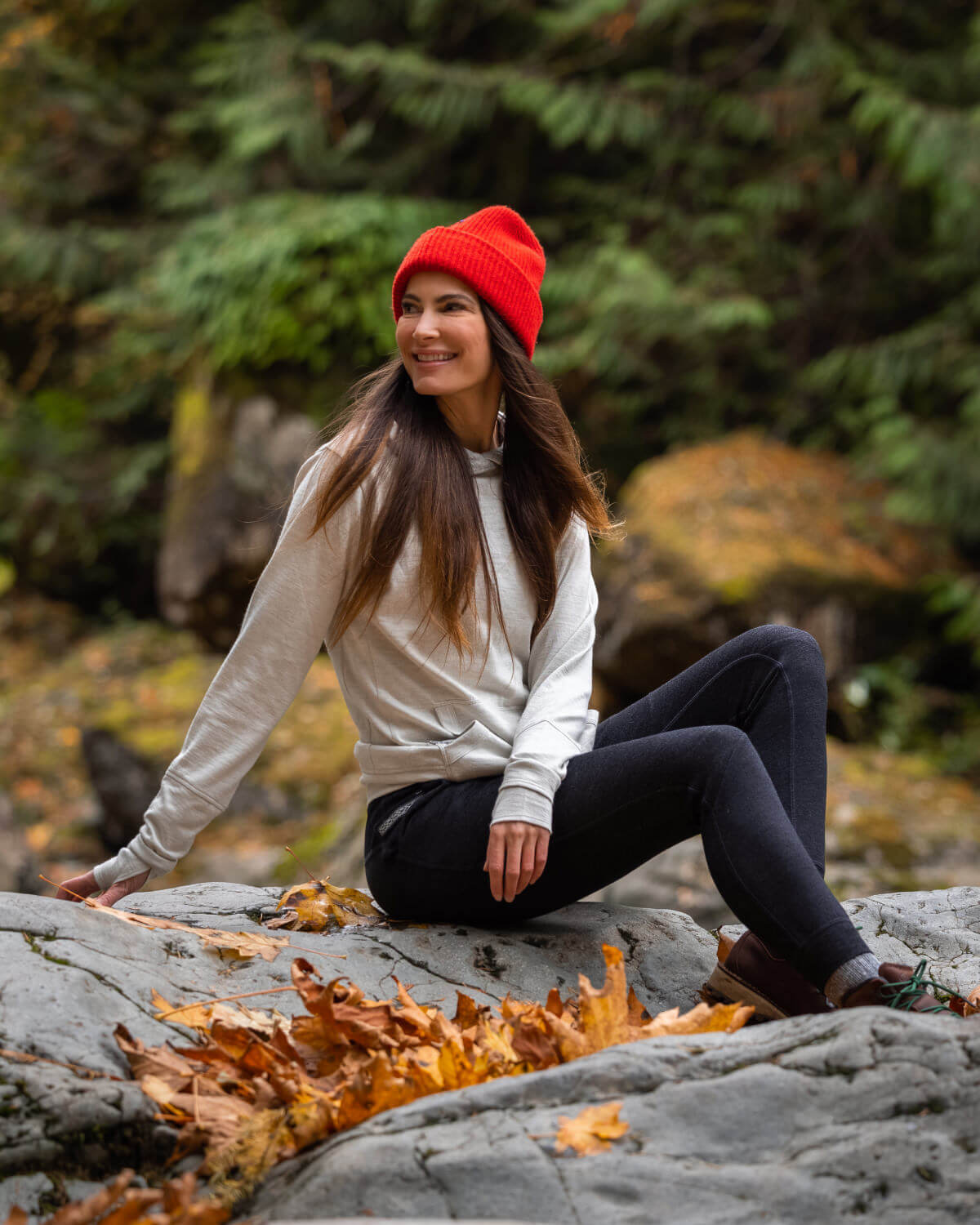 Smiling lady wearing an Ivory Breathe Hoodie and an orange beanie outdoors 