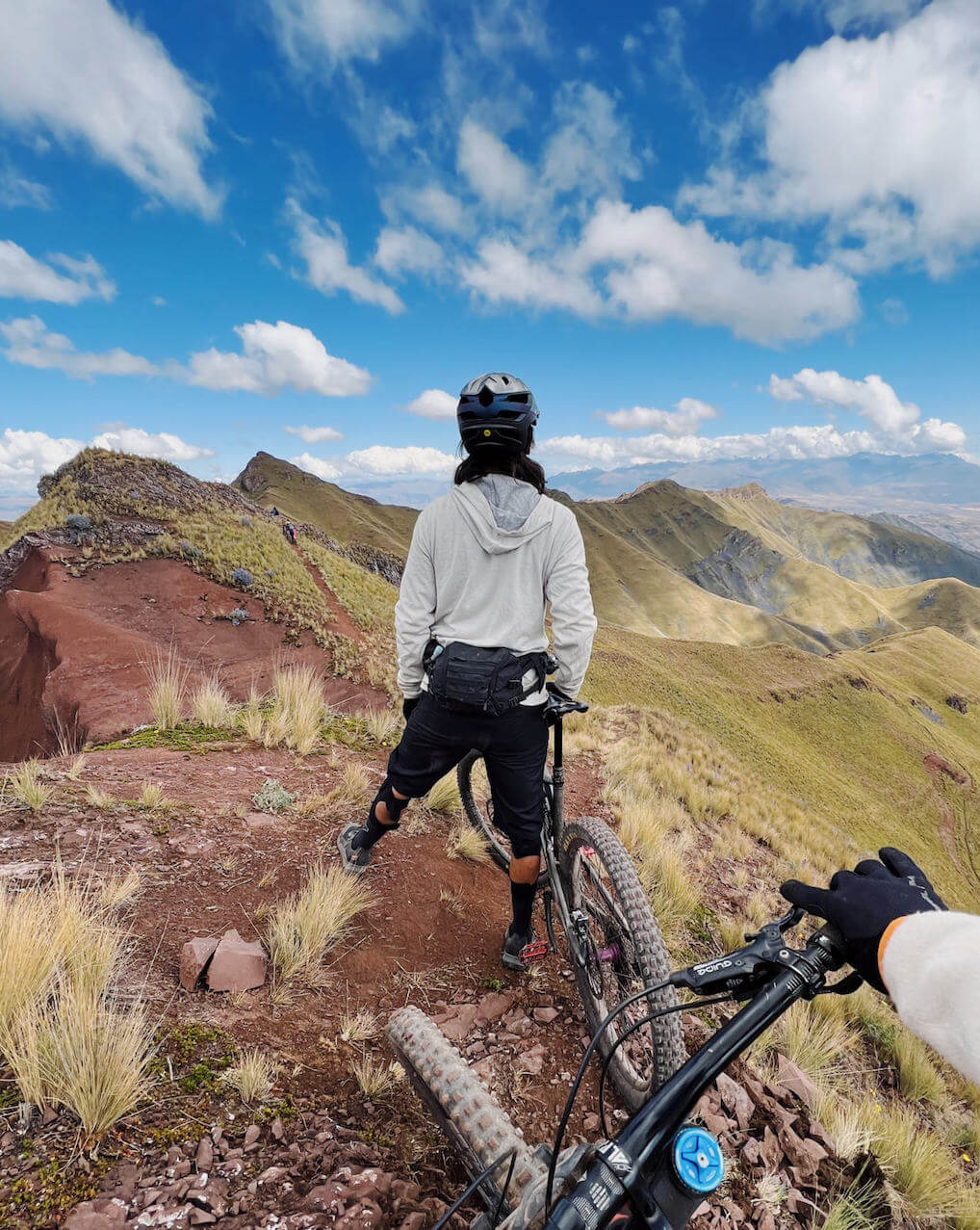 A man biking through the mountains in our Ivory Breathe Hoodie 