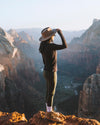 A lady wearing a hat and our alpaca baselayer in a canyon