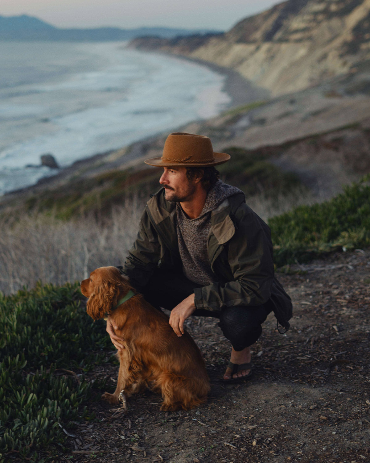 A man an his puppy looking at the ocean