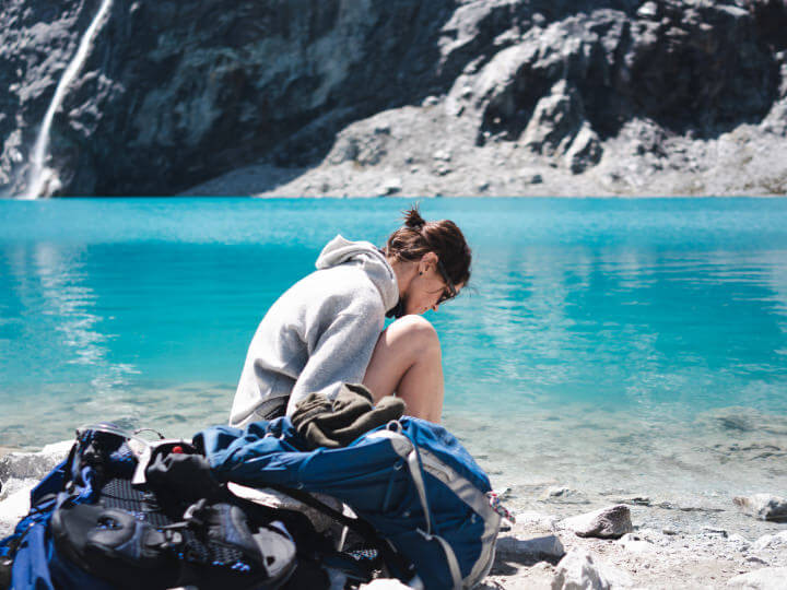 A person wearing an alpaca Hoodie in front of a mineral blue lake