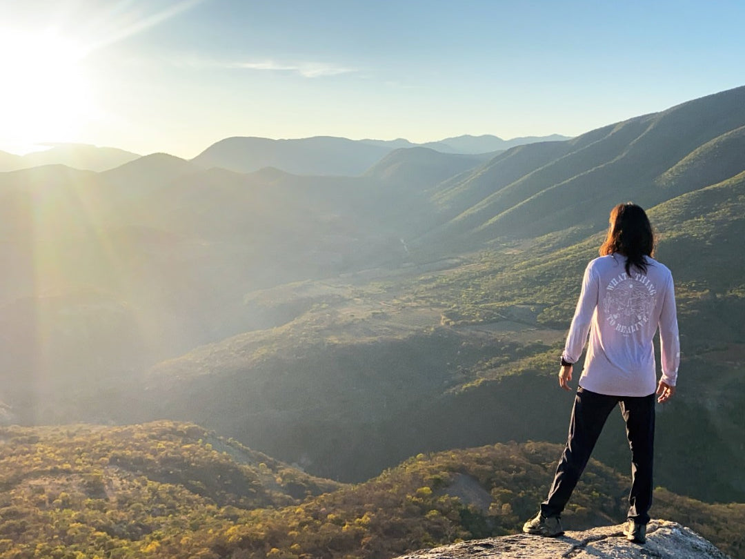 A woman wearing our Sebastian Baselayer looking at the mountains and the sunset