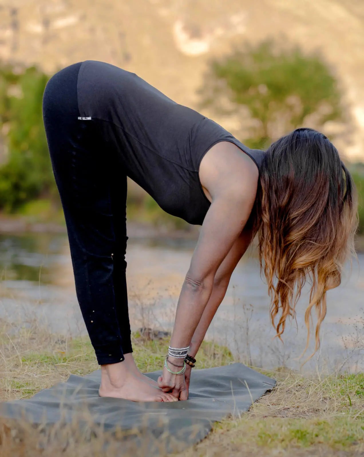 A woman wearing a black alpaca racer tank doing yoga poses