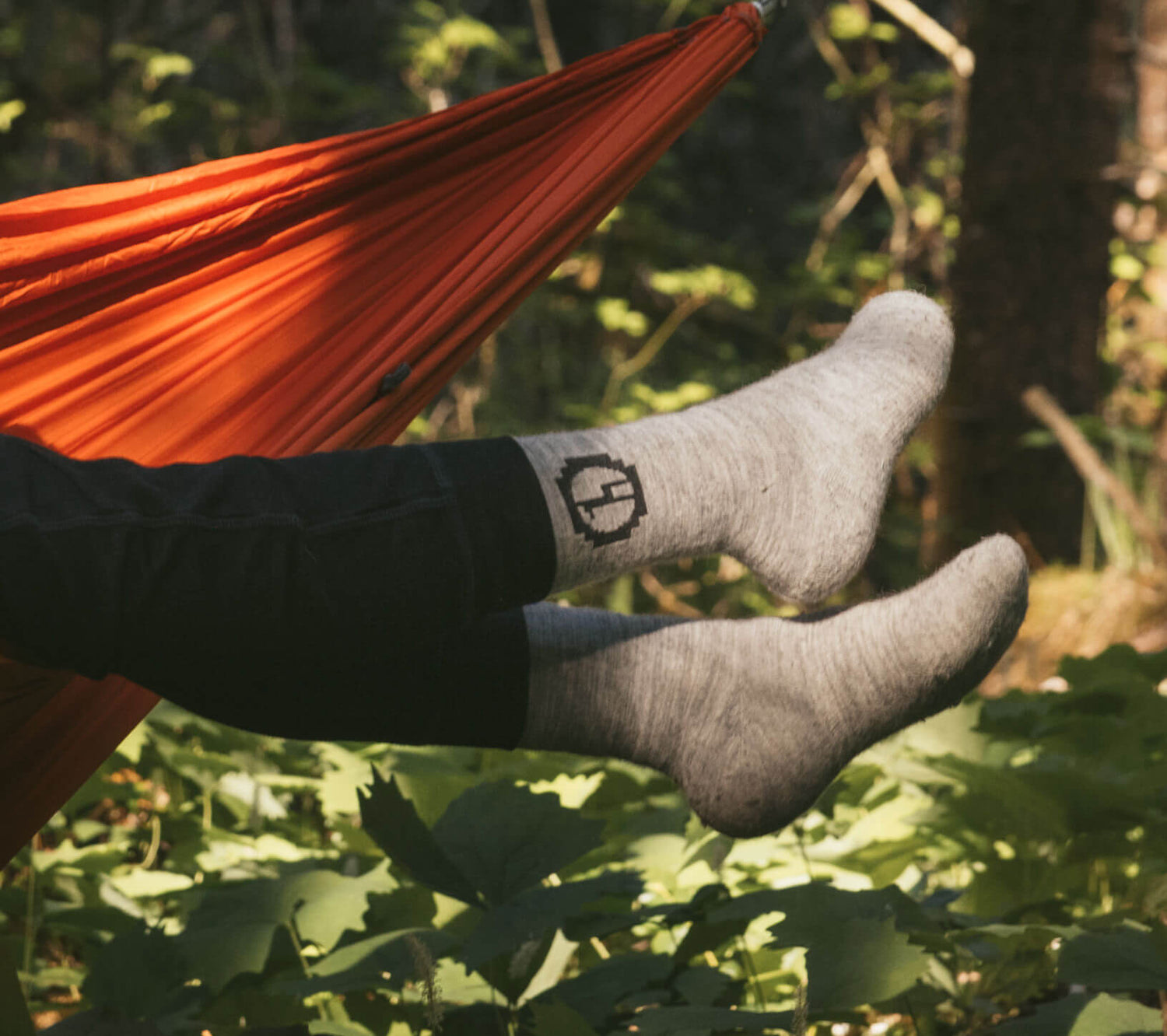 person in hammock hanging feet out and wearing grey alpaca socks