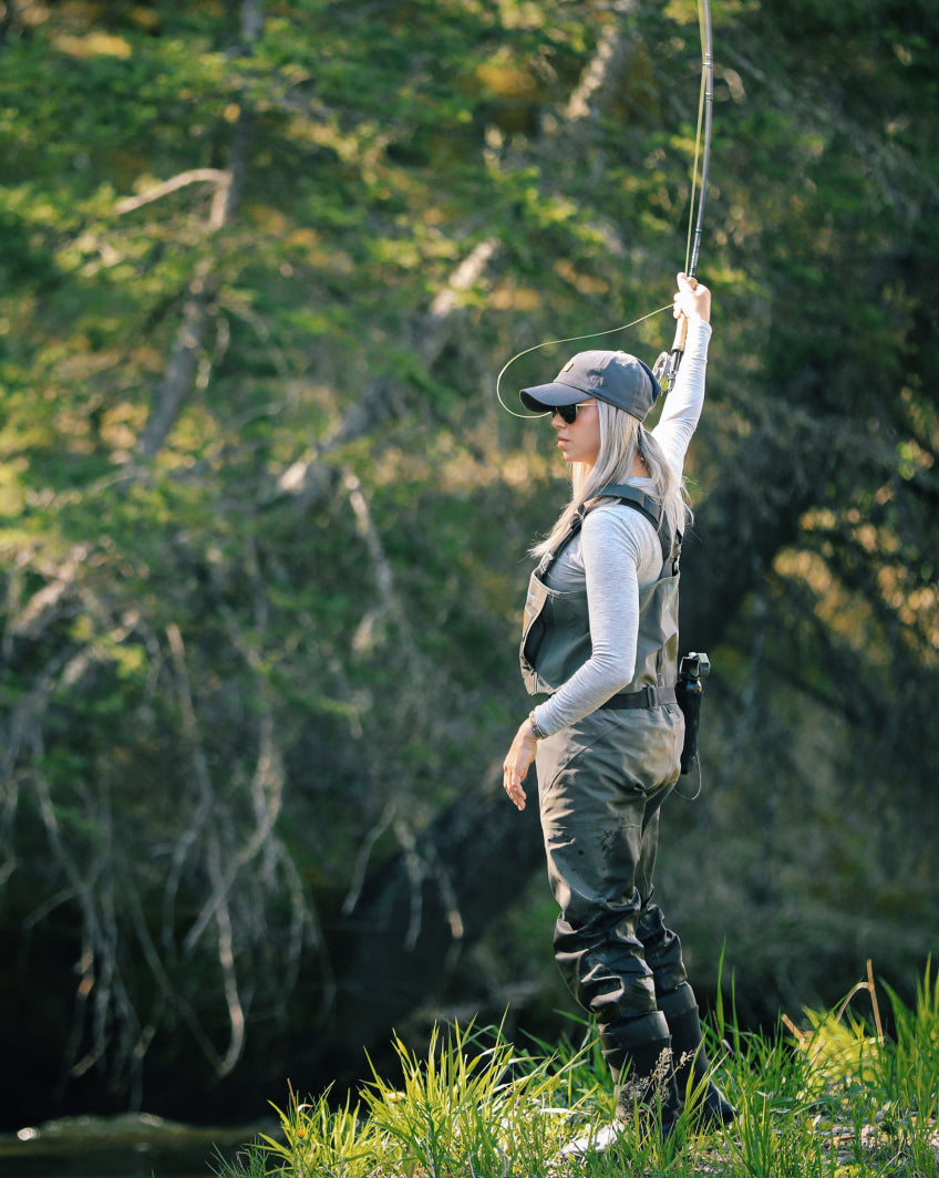 a woman with her fishing rod wearing a grey alpaca baselayer