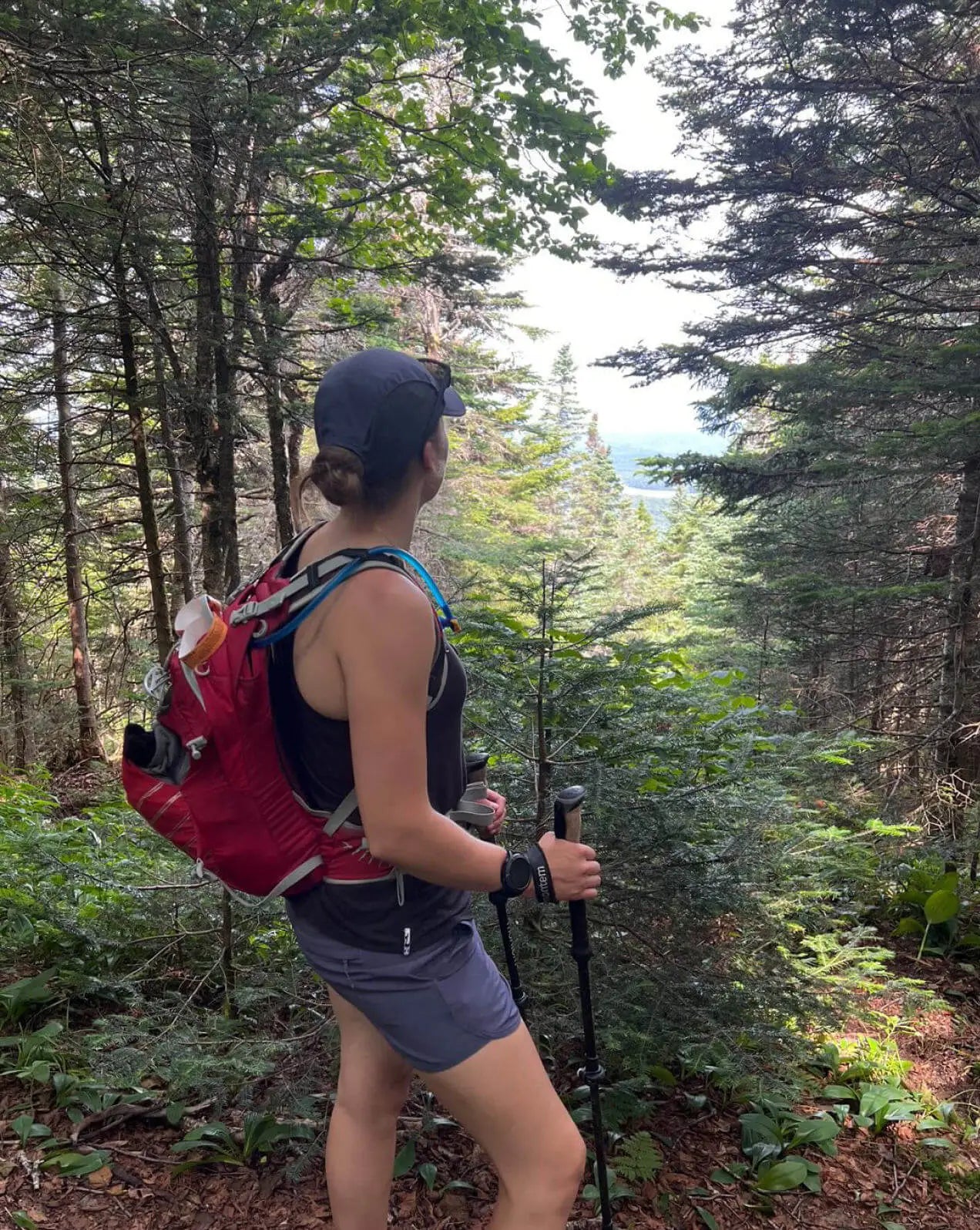 A woman wearing a black alpaca racer tank in the nature