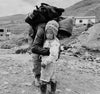 Noah carrying a backpack and hugging a small Quechua child wearing a Peruvian chullo