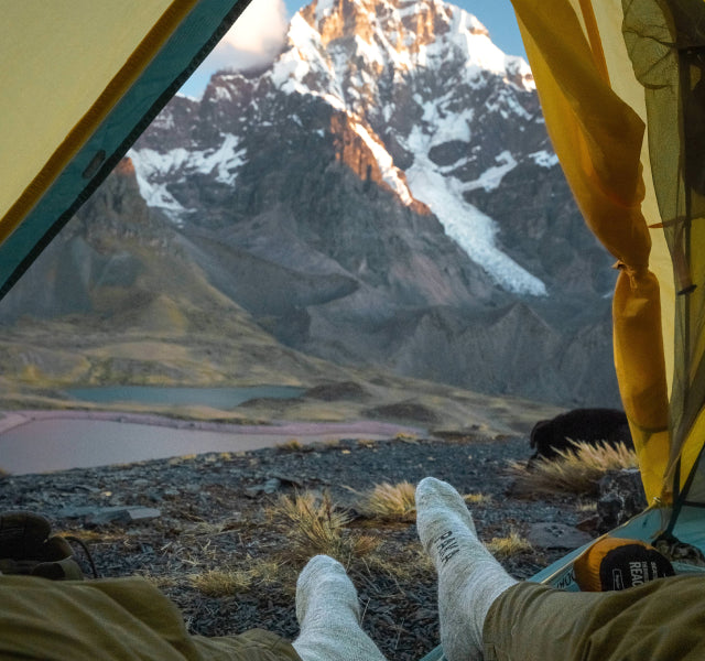 Alpaca socks sticking out of a tent with a view of Ausangate in the background. 